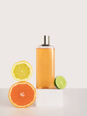 Shampoo or shower gel on a square podium, next to an orange, lemon and lime