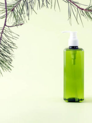 Bottle for cosmetics on a white podium pine branch on a light green background