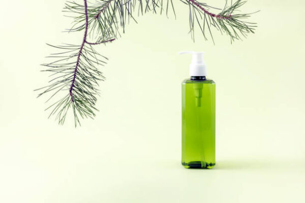 Bottle for cosmetics on a white podium pine branch on a light green background