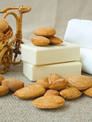 Soap bars with almond oil. almond nuts and white towels in the background.